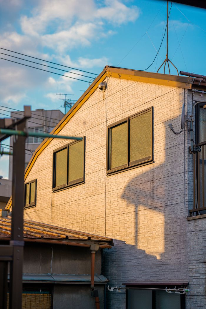 A modern Tokyo building bathed in warm sunset hues, showcasing urban residential architecture.