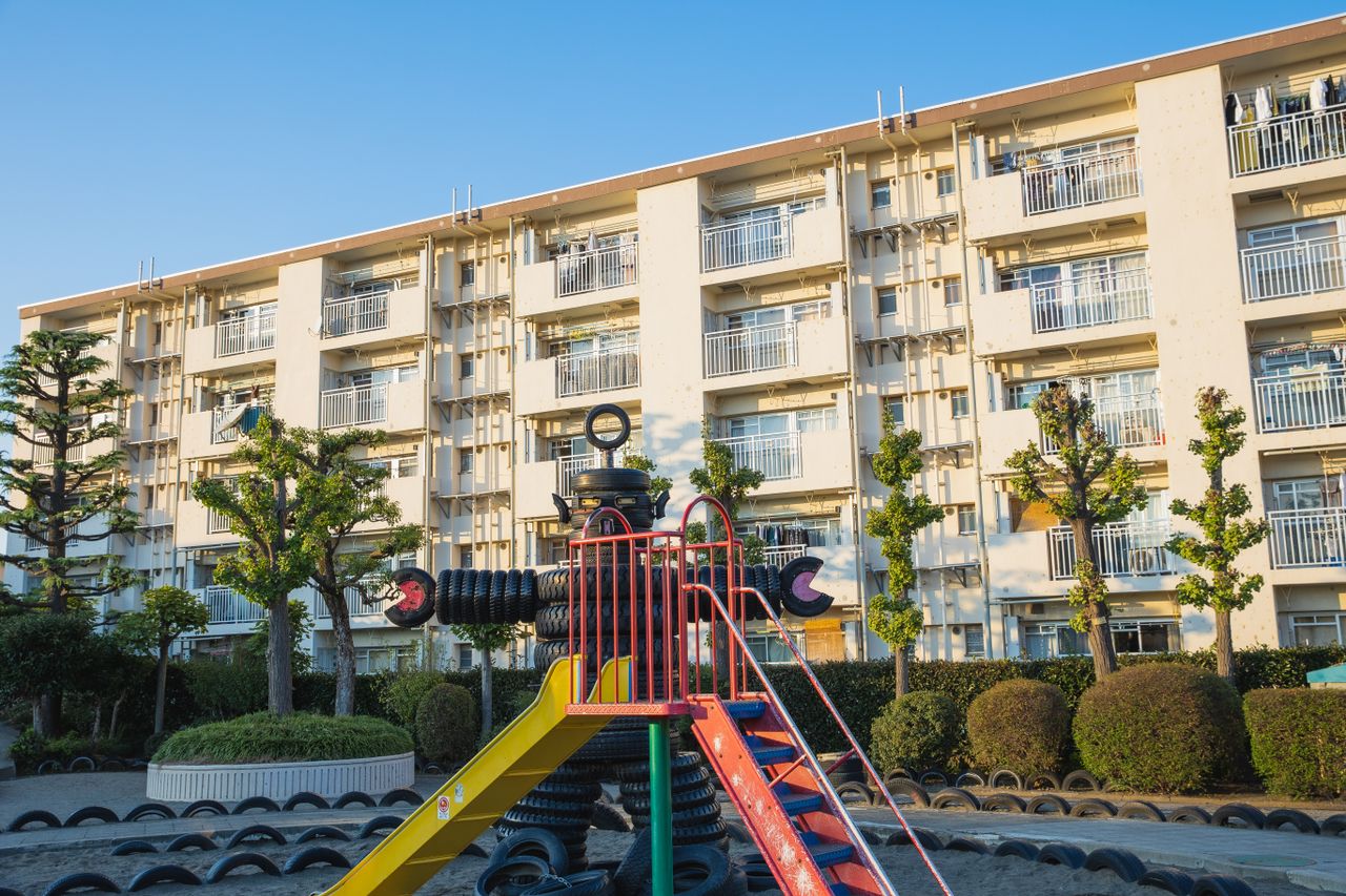 Playground in suburb yard with metal slide and huge robot made of pile of old rubber tyres